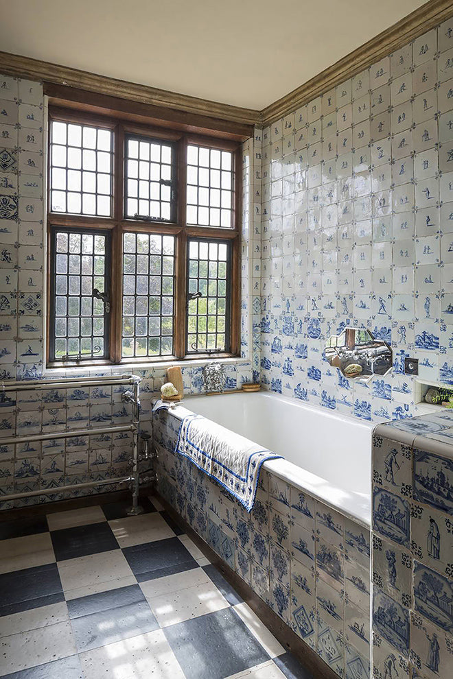 A primary bath in this 1780's English manor home is filled with antique Delft tiles.