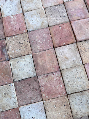 Reclaimed French terra cotta tile with centuries-old surface wear, irregular edges, pitting and naturally faded color