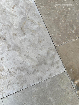 Architectural limestone flooring with warm beige and ash-gray tonal variation.