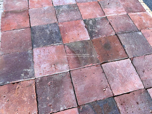 Reclaimed French terra cotta flooring with worn edges and deep aubergine & charcoal tones
