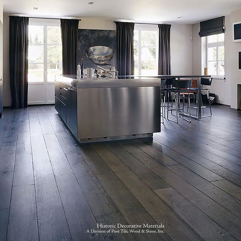 The cool stainless steel stovetop is a study in contrast with wide-plank warm brown gray vintage French oak floors.